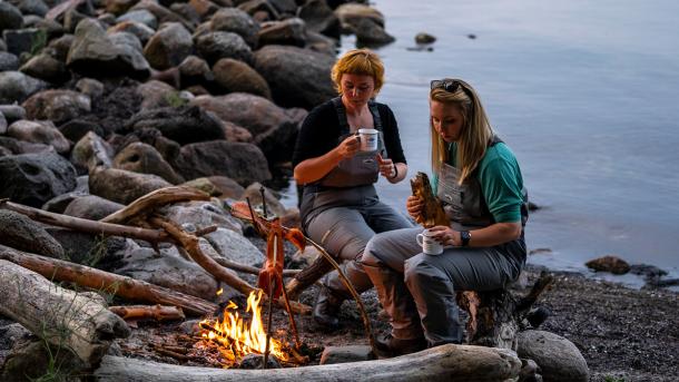 To kvinder der tilbereder deres fisk over bål