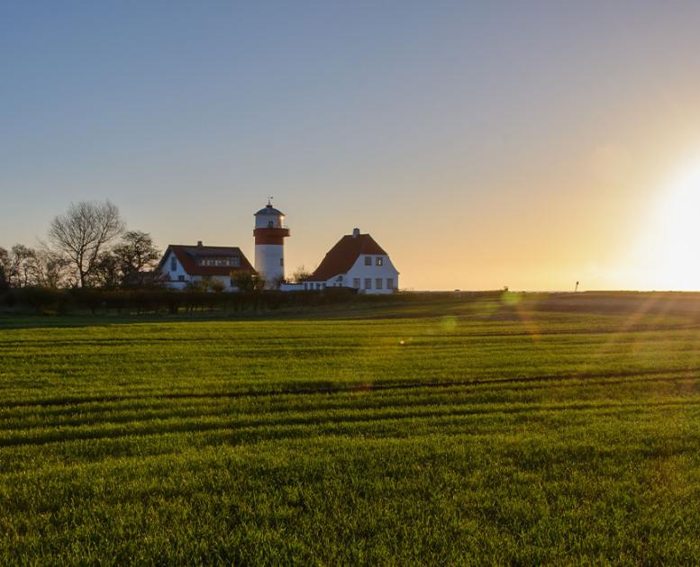 Solen står op på en dejlig forårsdag på Langeland og skinner over de grønner marker og fyrtårnet ved Hou,